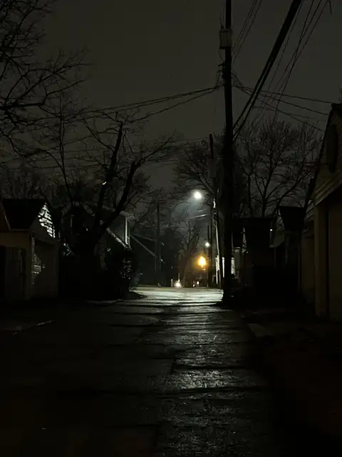 Wet pavement reflects the night's lonely glow.